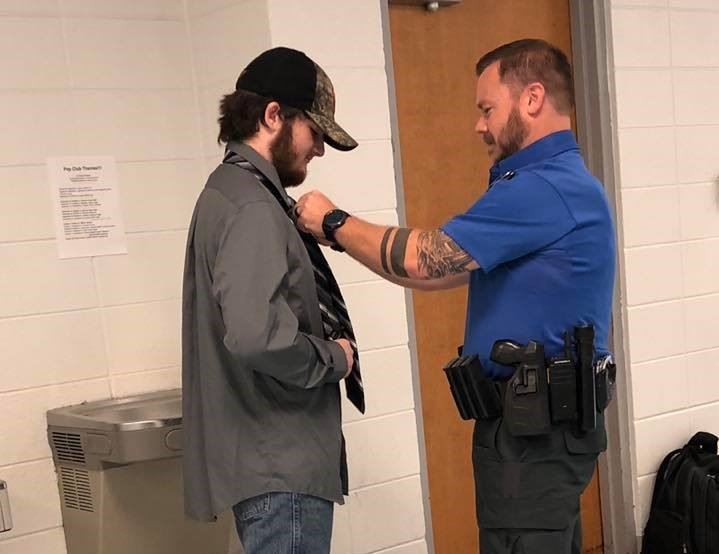 Officer Reed teaches student how to tie his tie